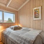 Schlafzimmer mit Holzwand, Bett, Schrank und Fenster.