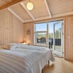 Schlafzimmer mit Holzwand, Bett und Balkonzugang.
