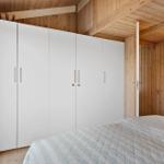 Schlafzimmer mit weißem Schrank und Holzwandverkleidung.