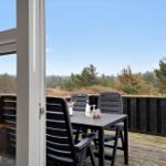 Terrasse mit Tisch und Stühlen, Blick auf Wald und Himmel.