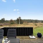 Terrasse mit Tisch, Stühlen und Blick auf Wiese und Wald.