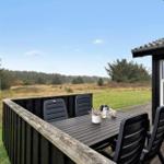 Terrasse mit Tisch und Stühlen, Blick auf Wiese und Wald.
