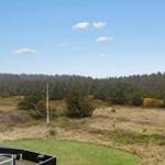Haus mit Blick auf Wald und Wiese unter blauem Himmel.