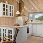 Küche mit weißem Schrank und Holzwand, Fenster mit Blick auf Grün