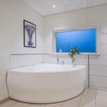 Bathroom with round bathtub, window, and heater.