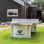 Ping pong table in the garden in front of a house with dark cladding.