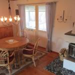 Esszimmer mit runder Tisch, Stühlen und Kamin. Fenster mit Vorhängen.