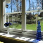 Fensterblick auf grünen Garten mit Laterne und blauem Glasvasen