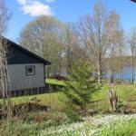 Haus mit Blick auf einen See, umgeben von Bäumen und Grünflächen.