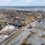 Strandnahe Ferienhäuser mit Blick aufs Meer und Sanddünen.