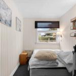 Schlafzimmer mit Bett, Fenster und Bücherregal an der Wand.