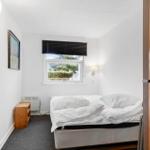 Schlafzimmer mit Bett, Fenster und Holzmöbel.