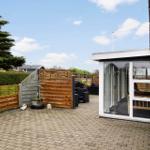 Hinterhof mit Steinplatten, Holzgeländer und Glasveranda. Gartenmöbel und Pflanzen sind sichtbar.