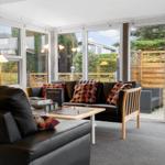Wohnzimmer mit Sofa, Couchtisch und großen Fenstern zur Außenterrasse.