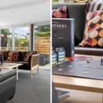 Wohnzimmer mit Sofa, Tisch und Brettspiel. Große Fenster mit Blick auf Garten.