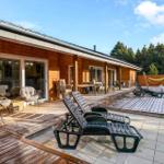 Wooden house with terrace, sun loungers, and view of forest.
