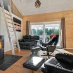 Living room with fireplace, black chairs, and wooden walls. Stairs to upper level.