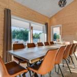 Dining room with wooden walls, large table and brown chairs. Large windows with view of garden.