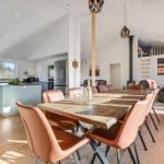 Dining area with wooden table and leather chairs. Kitchen with island and view of nature.