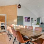 Large dining area with wooden table and brown chairs. Kitchen and grill area are visible.