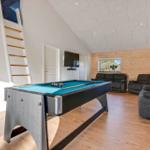 Pool table with blue felt, gray chairs, and wooden wall in living area.