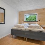 Bedroom with double bed, wooden wall, and window with view of trees.