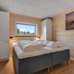 Bedroom with bed, window, and wooden wall. Wall picture of a deer.