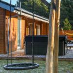 Wooden house with hot tub, swing, and hammocks in the garden