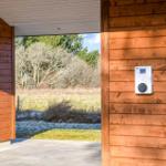 House with wooden wall and view of meadow and trees.