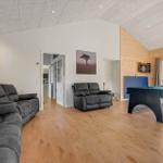 Large living room with pool table, sofa, and wood wall