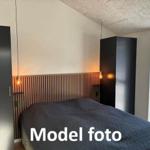 Bedroom with bed, two wardrobes, and wood panels on the wall.