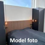 Bedroom with bed, dark cabinets, and wooden wall paneling.