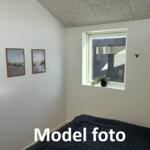 Bedroom with window, two pictures on the wall, and a bed with dark bedding.