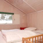 Schlafzimmer mit Holzwand, Fenster und Babybett.