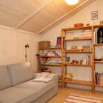 Wohnzimmer mit Sofa, Bücherregal und Holzwand