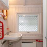 Badezimmer mit Waschbecken, Fenster und rotem Handtuchhalter.
