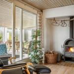 Wohnraum mit Kamin, Sitzgelegenheiten und Blick auf Terrasse.