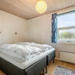 Schlafzimmer mit Bett, Fenster und Holzdecke.