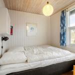 Schlafzimmer mit Bett, Fenster und Deckenleuchte.