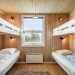Zwei Stockbetten mit Matratzen und Kissen. Holzwände und Boden. Fenster mit Blick nach draußen.