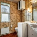 Badezimmer mit Waschmaschine, Toilette und Spiegel. Wandfliesen und Holzdecke.