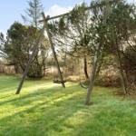 Hinterhof mit Schaukel und Grasfläche unter Bäumen