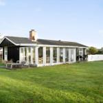 Moderne Villa mit großem Garten und Terrasse. Glasfront zeigt Wohnbereich.