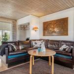 Ein Wohnzimmer mit braunem Ledersofa, Holztisch und Wandbild.