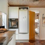 Küche mit integriertem Ofen und Kühlschrank. Durchgang zu Schlafzimmer mit Hochbett.