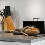 Küchenarbeitsfläche mit Brot, Messer und Küchenutensilien.