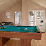 Room with pool table, sofa, and white cabinets. Wooden walls and ceiling.