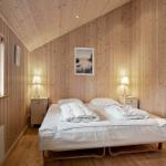 Bedroom with wood paneling, bed, and window with view of forest.
