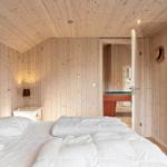 Bedroom with wooden walls and bed. Passage to room with billiard table.