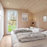 Bedroom with wooden walls, bed, and window overlooking greenery.
